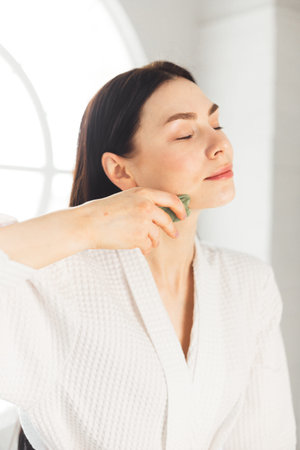 Young woman doing face Gua sha - chinese traditional massageの写真素材