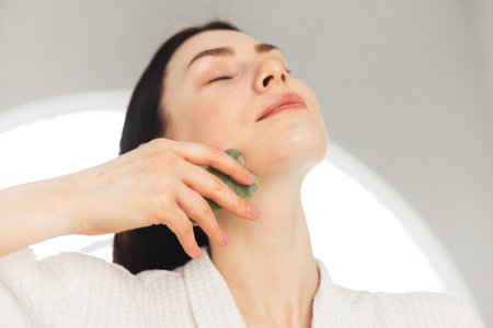 Young woman doing face Gua sha - chinese traditional massageの写真素材