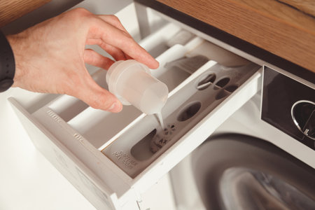 Man pouring the washing fabric conditioner into the washing machine to get more softer clothes.の写真素材