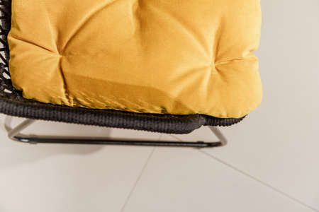 Black wicker chair with yellow pillows. Detailsの写真素材