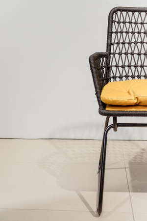 Black wicker chair with yellow pillows. Detailsの写真素材