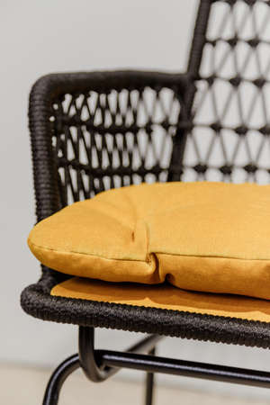 Black wicker chair with yellow pillows. Detailsの写真素材