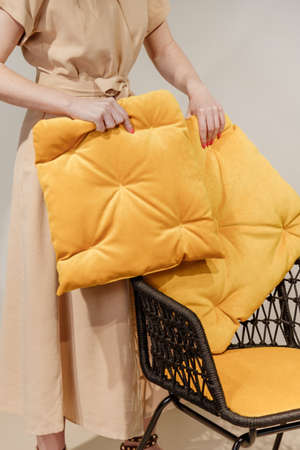 Woman puts pillows on modern wicker armchairの写真素材