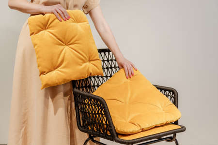 Woman puts pillows on modern wicker armchairの写真素材