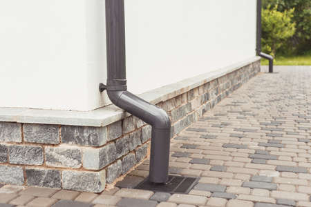 stormwater pipe on facade with rainwater drainage into drainage system with sewer manhole grillの写真素材