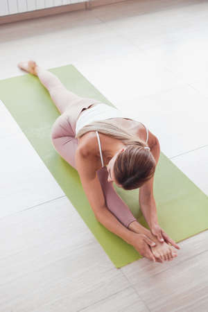 The sports girl the trainer is warming up is engaged in stretching sits on the twineの写真素材