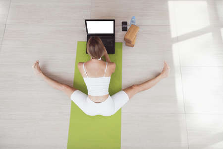 Young fit woman in sportswear doing sport or yoga online with laptop. Remote workouts, online trainer. Top view. Laptop with blank screenの写真素材