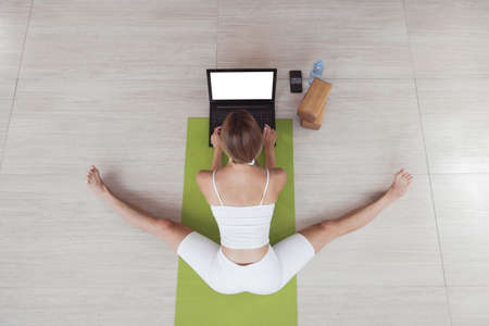 Young fit woman in sportswear doing sport or yoga online with laptop. Remote workouts, online trainer.の写真素材