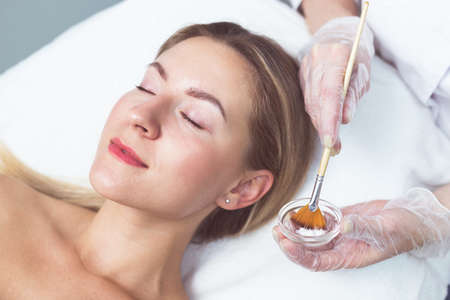 Beautician applying facial mask to the young ladyの写真素材