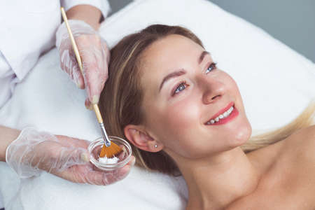 Beautician applying facial mask to the young ladyの写真素材