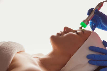 Young woman getting ultrasound skin cleansing and face treatment at beauty salonの写真素材