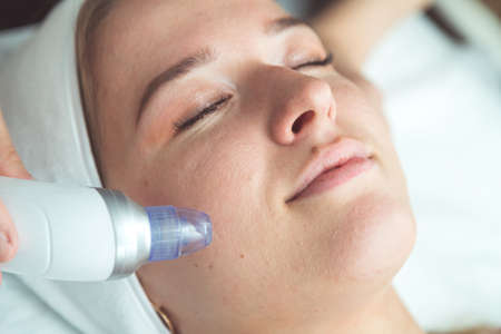 closeup portrait of happy redheaded woman with closed eyes getting rf-lifting in a beauty salonの写真素材