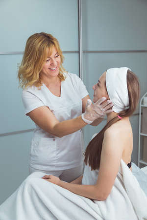 Doctor examining young woman face before cosmetic proceduresの写真素材