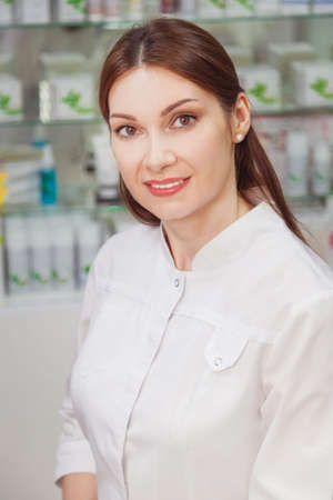 woman doctor pharmacist beautician in the office on the background of shelves with medicines.の写真素材