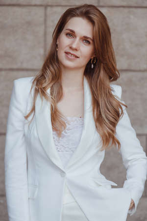 Confident elegant woman in white blazer outdoors looking away. Business style.の写真素材