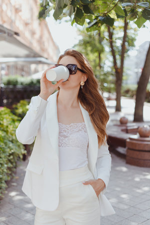 Portrait of business woman walking with take away paper cup outdoorsの写真素材