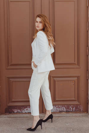Young elegant woman in white blazer, pants and black heelsの写真素材