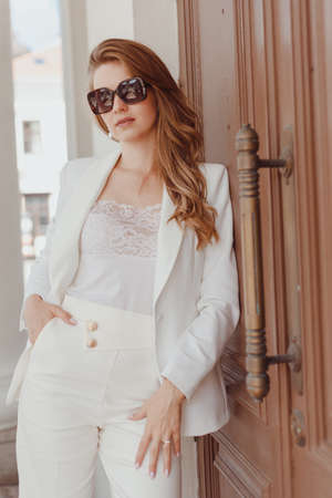 Woman in white stylish blazer and pants and sunglasses. Elegant women white outfitの写真素材