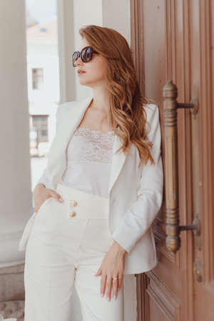 Woman in white stylish blazer and pants and sunglasses. Elegant women white outfitの写真素材
