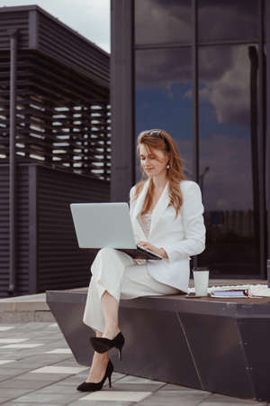Portrait of cute young business woman outdoorwith coffee and laptopの写真素材