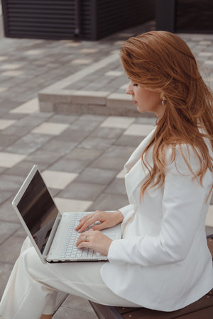 Young business woman in white suit working outdoor on laptopの写真素材