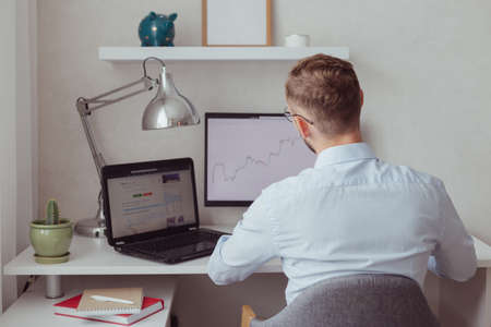 Stock trader looking at monitors, back view.の写真素材