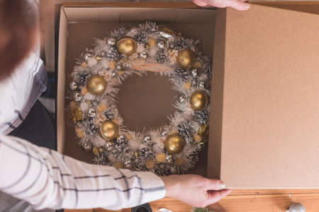 Female artisan is packing a Christmas wreath in a box to be sent to the customer. Delivery, manual work, work with orders. small business conceptの写真素材