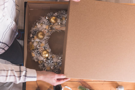 Female artisan is packing a Christmas wreath in a box to be sent to the customer. Delivery, manual work, work with orders. small business conceptの写真素材