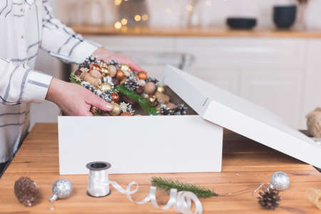 Female artisan is packing a Christmas wreath in a box to be sent to the customer. Delivery, manual work, work with orders. small business conceptの写真素材