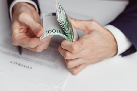 Man in suit counts wad of money before signing contract. Close up of hands with money euroの写真素材