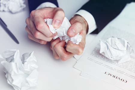 Stressed businessman crumple paper contract and documents - failed deal and crisis concept.の写真素材