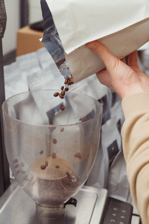 Weighing coffee grains on digital scale. Hands of female barista pouring roasted coffee grains on a scale before brewing coffee.の写真素材