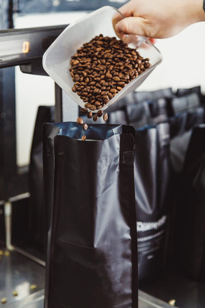 Man scales roasted coffee beans, pour into package for sale.