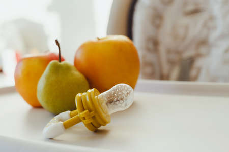 Nibbler with fresh apples and pear on light kids table, closeup. baby feeder.の写真素材