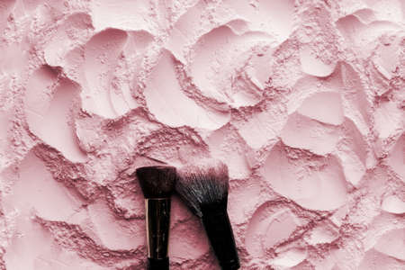 Makeup brushes on pink cosmetic powder background. Flat lay, top view.の写真素材