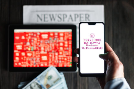 New York, USA - January 19. 2022: Berkshire Hathaway logo mobile phone, Stock market map, newspaper...