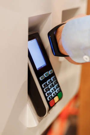 man hand use smart bracelet or smartwatch to make contactless payment over nfc technology, apply to payment terminal. Concept e-commerce, people using contact less technology, business, cashless.の写真素材