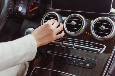 Hand of woman turning on car air condition system,Button on dashboard in car panel,Auto car air...