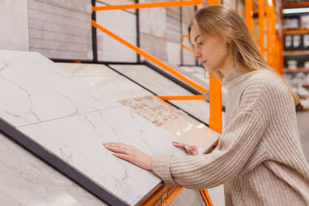 Woman choosing ceramic tile in hardware storeの写真素材