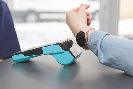 Customer making wireless or contactless payment using smartwatch. Store worker accepting payment...