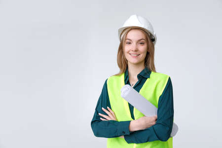 Woman engineer builder in white hard hat with blueprints and tablet folderの写真素材