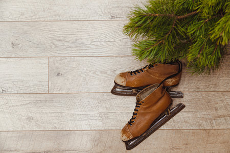 Old leather skates and fir branches on wooden background, winter conceptの写真素材