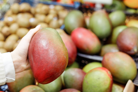 Young Woman Choosing Mango in Grocery Store. Concept of healthy food, bio, vegetarian, diet.の写真素材