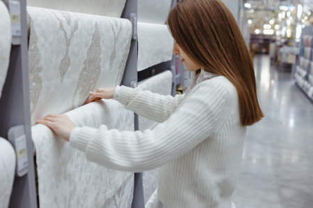Young woman choose wallpaper in hardware store. Home design and renovation concept.の写真素材