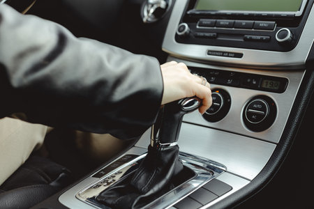 Driver holds on to the shift lever of the automatic transmission. A woman changes gear in a car.の写真素材