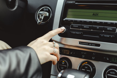 Woman turns on media radio in a carの写真素材