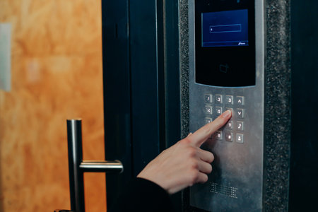 Woman hand press buttons on video intercom at entrance of apartment building in the night. Password entersの写真素材