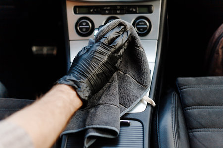 Mans hand in black glove cleaning car interior, dashboard and leather seats with microfiber clothの写真素材