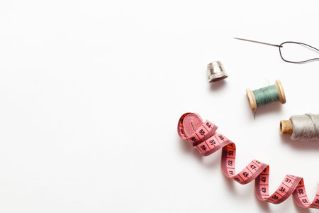 Old Vintage Thimble, measuring tape and threads isolated on white background, top view.