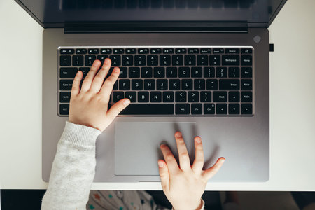 Childs hand on laptop computer keyboard. Access to information, protection, and usability